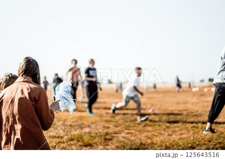Selective focus on a pom-pom streamer with defocused child running in the background  125643516