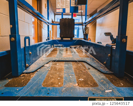 open gate to a scissor lift lowered inside a building construction project.  125643517