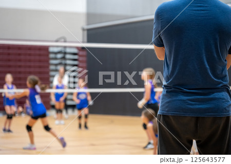 Selective focus behind a coach at a youth volleyball match, blurred game. Selective focus behind a coach at a youth volleyball match, blurred game. 125643577