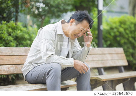 公園のベンチで落ち込むミドル男性 125643676