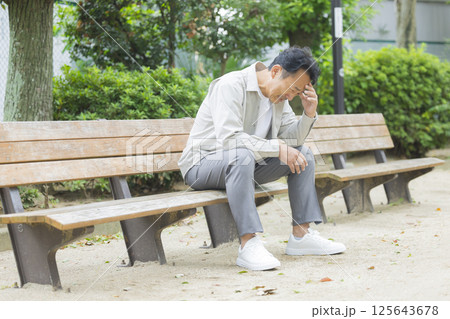 公園のベンチで落ち込むミドル男性 公園のベンチで落ち込むミドル男性 125643678