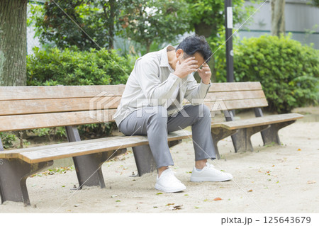 公園のベンチで落ち込むミドル男性 公園のベンチで落ち込むミドル男性 125643679