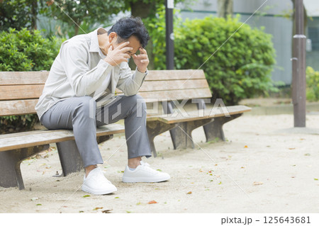 公園のベンチで落ち込むミドル男性 125643681