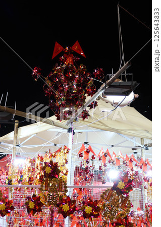 Chinese New Year  red and gold windmills hanging on the rack being sold in the Lunar New Year market outdoor at night. The windmills will bring luck 125643833