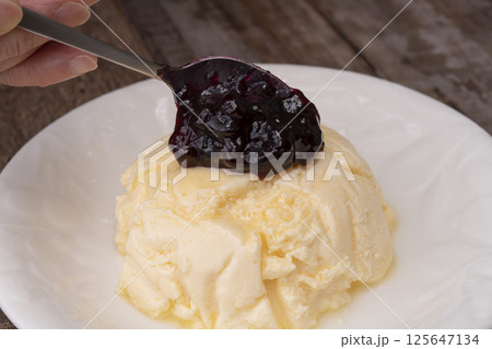高タンパクなギリシャヨーグルトを使ったケーキにブルーベリーソースをかけて仕上げる 125647134