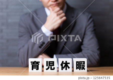 育児休暇のブロックとスーツを着て悩むミドル男性ビジネスマン 育児休暇のブロックとスーツを着て悩むミドル男性ビジネスマン 125647535