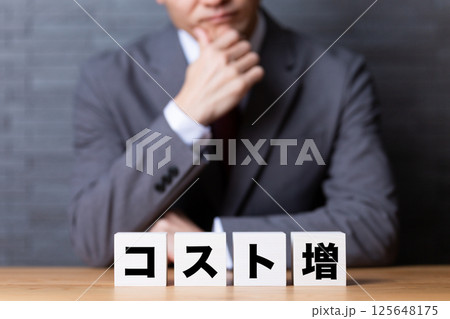 コスト増のブロックとスーツを着て悩むミドル男性ビジネスマン 125648175