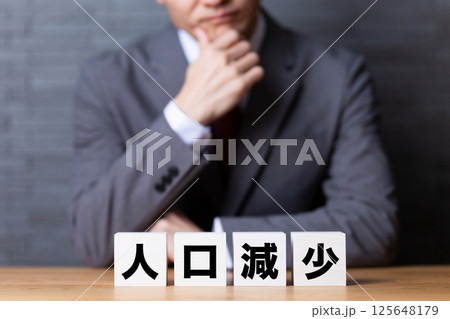 人口減少のブロックとスーツを着て悩むミドル男性ビジネスマン 人口減少のブロックとスーツを着て悩むミドル男性ビジネスマン 125648179
