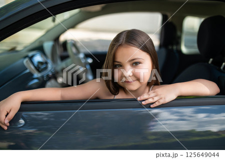 Child girl looking out car window during road trip on summer vacations Child girl looking out car window during road trip on summer vacations 125649044