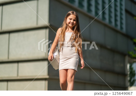 Cute little child walking through the urban street on her way to school carrying backpack 125649067