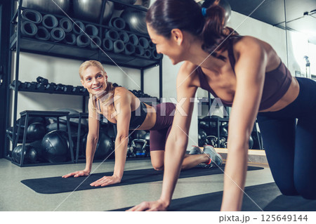 Young women doing stretching on the mats in the gym Young women doing stretching on the mats in the gym 125649144