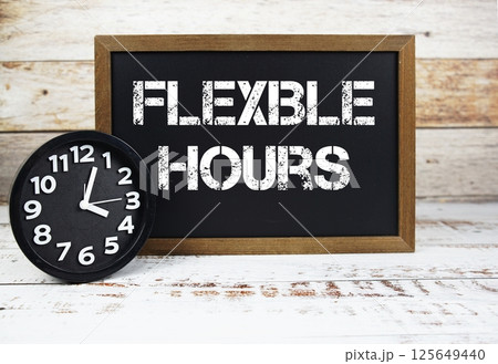 Flexible Hours text message and alarm clock on wooden background 125649440