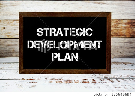 Strategic Development Plan text message and alarm clock on wooden background Strategic Development Plan text message and alarm clock on wooden background 125649694