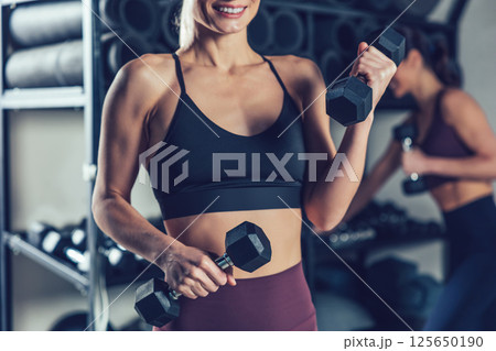 Fit and sporty young caucasian women with dumbbells in the gym 125650190