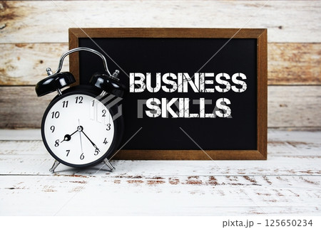 Business Skills text message and alarm clock on wooden background Business Skills text message and alarm clock on wooden background 125650234