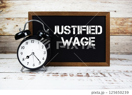 Justified Wage text message and alarm clock on wooden background Justified Wage text message and alarm clock on wooden background 125650239