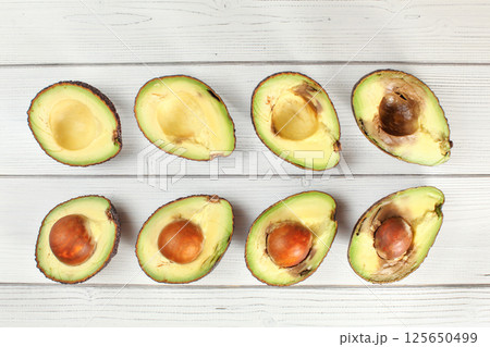Avocado halves arranged from ripe to over ripen on white boards desk, view from above 125650499