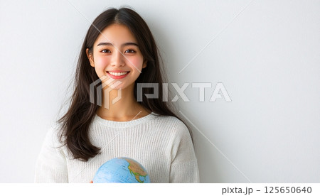 Young woman smiles while holding a globe, symbolizing travel, exploration, and global awareness  125650640
