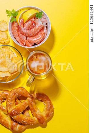 A vibrant photo showcasing a glass of beer surrounded by various snacks and fast food 125651441