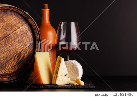 A refined selection of aged cheeses presented on a board, accompanied by a glass of wine A refined selection of aged cheeses presented on a board, accompanied by a glass of wine 125651486