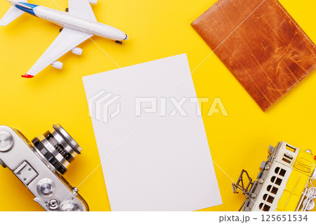 Travel-themed flat lay with blank photo card, camera, toy airplane, and passport Travel-themed flat lay with blank photo card, camera, toy airplane, and passport 125651534