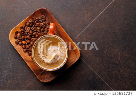 A steaming cup of freshly brewed coffee surrounded by rich, aromatic roasted coffee beans A steaming cup of freshly brewed coffee surrounded by rich, aromatic roasted coffee beans 125651727