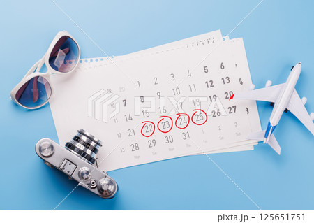 Travel-themed flat lay with calendar, toy airplane, camera, and sunglasses Travel-themed flat lay with calendar, toy airplane, camera, and sunglasses 125651751