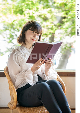 新緑が見える部屋で読書をする若い女性 新緑が見える部屋で読書をする若い女性 125651983