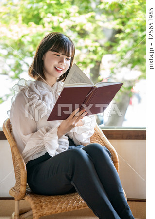 新緑が見える部屋で読書をする若い女性 125651985