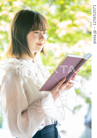 新緑の中で読書をする若い女性 125652071