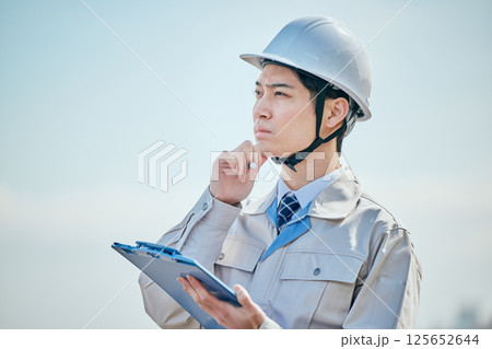 メモを取る作業着姿の20代の若い男性 メモを取る作業着姿の20代の若い男性 125652644