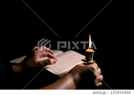 In the church, candle flickered beside cross as Christians gathered to pray, their faith in Jesus and spiritual devotion illuminated by Bible in background, deepening their Catholic worship. In the church, candle flickered beside cross as Christians gathered to pray, their faith in Jesus and spiritual devotion illuminated by Bible in background, deepening their Catholic worship. 125653404