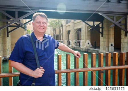 Adult blond man traveling in Venice, standing above water canal 125653573