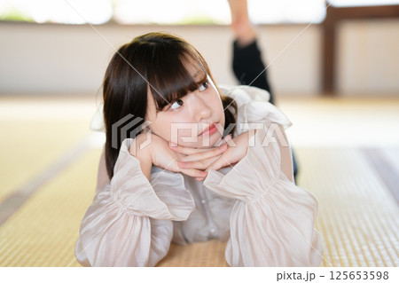 畳に寝転んでくつろぐ若い女性 畳に寝転んでくつろぐ若い女性 125653598