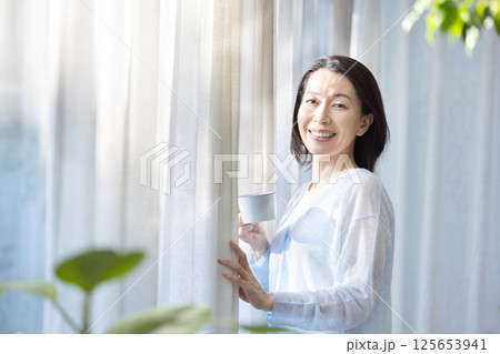 窓辺でコーヒーを飲む女性 125653941