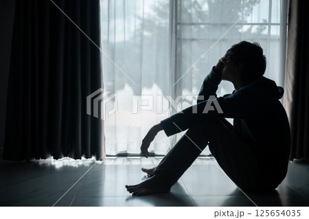 Silhouette of lost cast long shadow, embodying deep despair and hopelessness left him feeling perpetually stressed, sad, and unhappy. man sat alone, feeling weight of anxiety, stress, and depression. 125654035