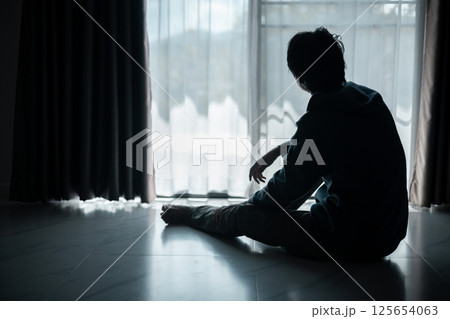 Silhouette of lost cast long shadow, embodying deep despair and hopelessness left him feeling perpetually stressed, sad, and unhappy. man sat alone, feeling weight of anxiety, stress, and depression. 125654063