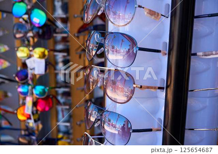 A close-up of sunglasses displayed on a stand, reflecting palm trees and a sunny street. 125654687