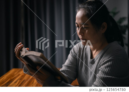 Woman bowed her head in prayer, her hand clasped in faith, as she prayed to Jesus Christ for hope, peace, and the guiding presence of God in her religion. god, religion, faith, hope, peace, christian. 125654780