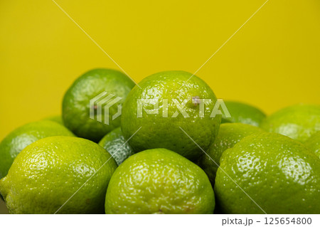Whole fresh limes fruit on yellow background close-up. Whole fresh limes fruit on yellow background close-up. 125654800