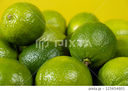 Whole fresh limes fruit on yellow background close-up. 125654801