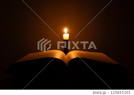 Candle with bible on a old oak wooden table. Beautiful gold background. Religion concept. 125655101