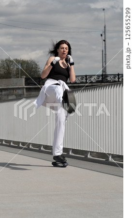 A woman engages in an intense workout, kicking with precision while maintaining stability on jumping shoes. This image represents athleticism, focus, and modern fitness trends. A woman engages in an intense workout, kicking with precision while maintaining stability on jumping shoes. This image represents athleticism, focus, and modern fitness trends. 125655299