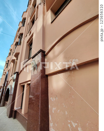A modern peach building with air conditioning units and round red accents against sharp architectural lines. The image emphasizes urban geometry, structural forms, and contrasting functional elements. 125656310