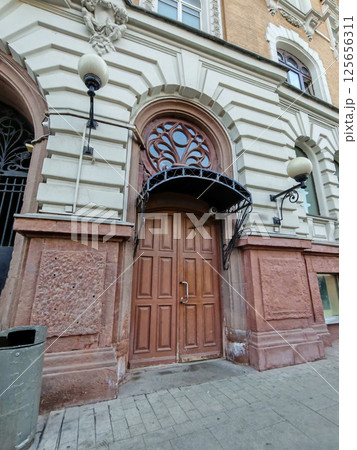 An aged wooden door surrounded by carved stonework and topped with a wrought-iron canopy. The image conveys themes of timeless design and urban heritage. 125656311
