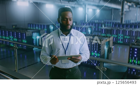 Big Data Center with Server Racks: Professional Specialist Using Tablet Computer, Activating Servers 125656493