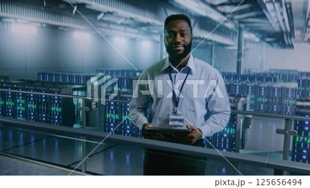Big Data Center: Specialist with Tablet Computer Standing in Storage, Looking at Camera 125656494