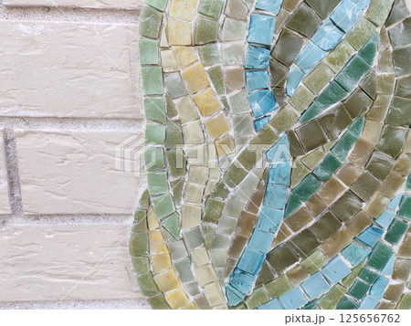 An artistic mosaic of small tiles in natural shades of blue, green, and yellow. The intricate arrangement creates a visually engaging texture. 125656762