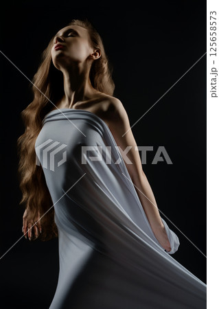 Woman poses confidently in flowing garment during casting session indoors Woman poses confidently in flowing garment during casting session indoors 125658573