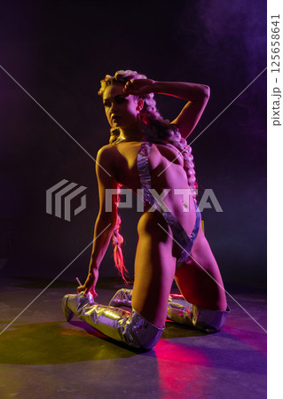 Woman in silver body art poses creatively in lingerie under colorful lights Woman in silver body art poses creatively in lingerie under colorful lights 125658641